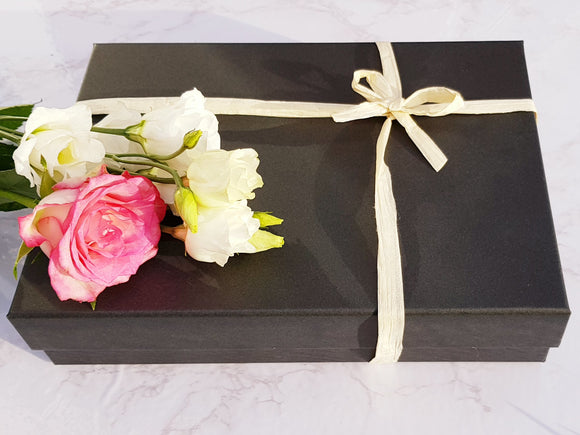 A luxury gift box, closed and tied with paper ribbon and decorated with flowers