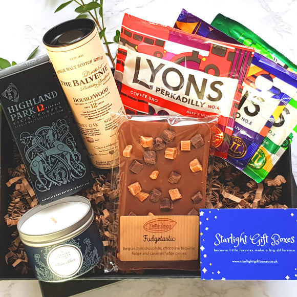 An opened gift box showing a bottle of Balvenie single malt whisky, a bottle of Highland Park single malt whisky, a handmade Belgian chocolate slab, a tin candle and a trio of coffee
