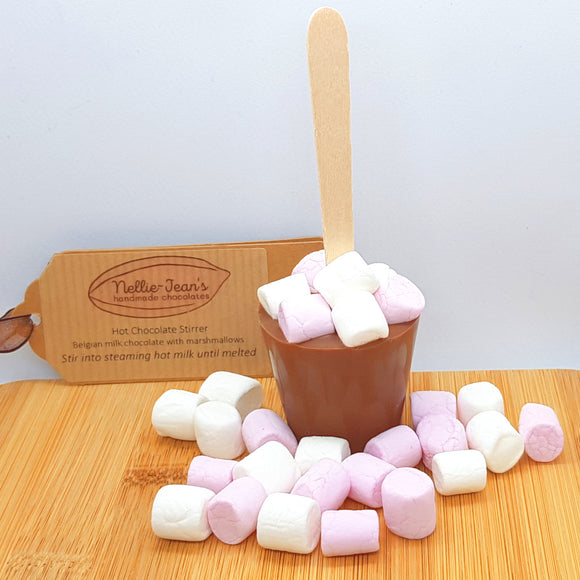 A hot chocolate stirrer scattered with mini marshmallows and with a Nellie-Jean's label