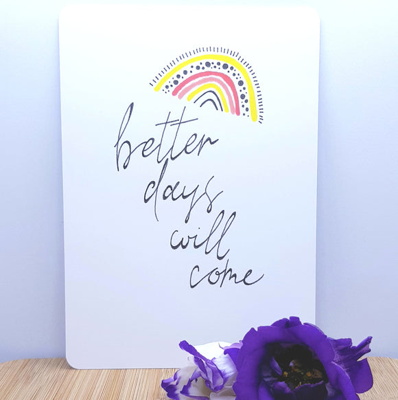 An A5 card showing a rainbow with better days will come written on it, decorated with a purple flower in front