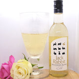 A bottle of Jack Rabbit Sauvignon Blanc next to white wine in a glass, decorated with two flowers