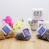  Three different flavoured tea bags, with their boxes behind, decorated with a flower