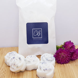 Five rose shaped wax melts in front of a biodegradable glassine packet