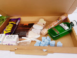 An open letterbox friendly gift box showing contents of a Cadbury Twirl, a sachet of hot chocolate, bath bombs, bath salts, a bottle or Gordon's gin, some wax melts and two tea boxes