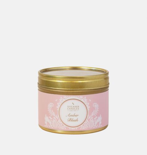 An amber blush fragrant candle in a tin with the lid on