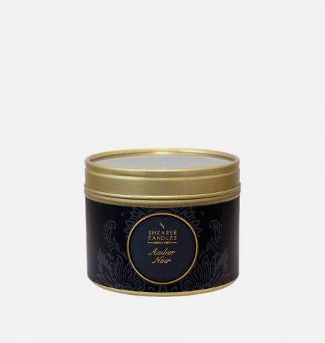 An amber noir fragrant candle in a tin with the lid on