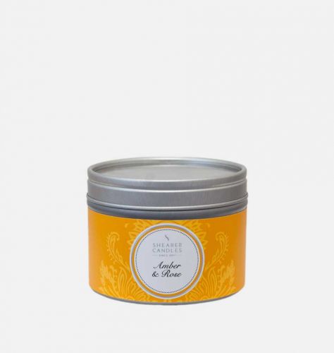 An amber and rose fragrant candle in a tin with the lid on
