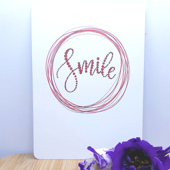 An A5 card showing a red circle with smile written on it, decorated with a purple flower in front